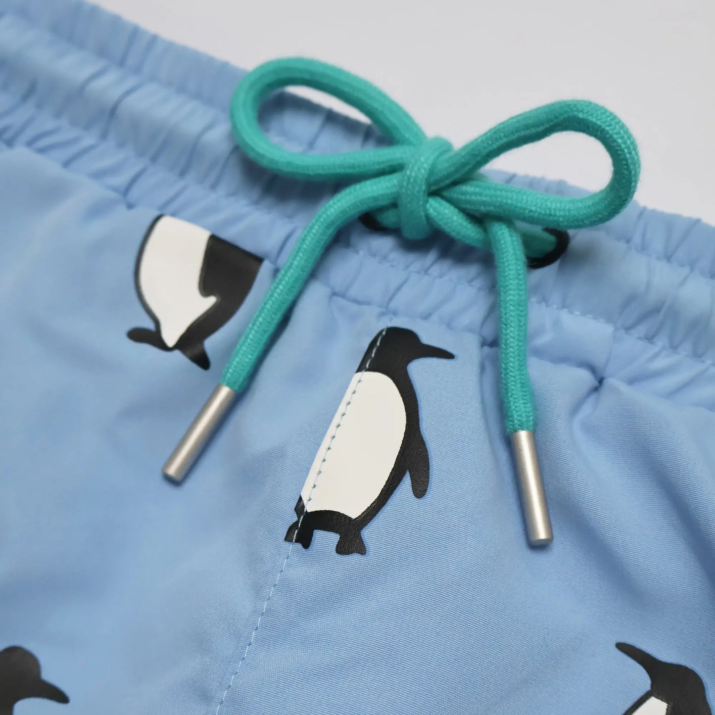Holly and Beau light blue penguin boys color changing swim trunks. Front detail drawstrings