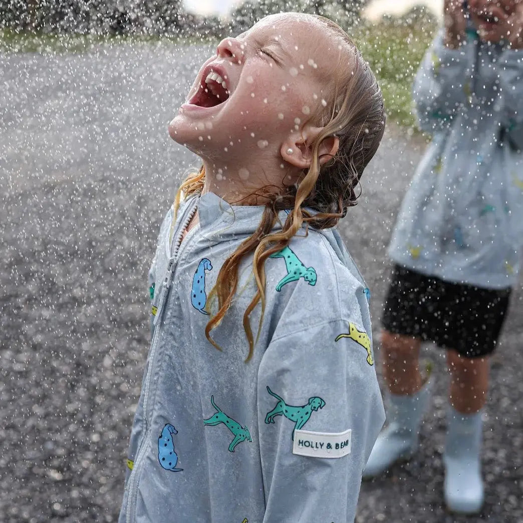 Holly and Beau Lifestyle image of girl wearing the dalmatian color changing raincoat standing in the rain