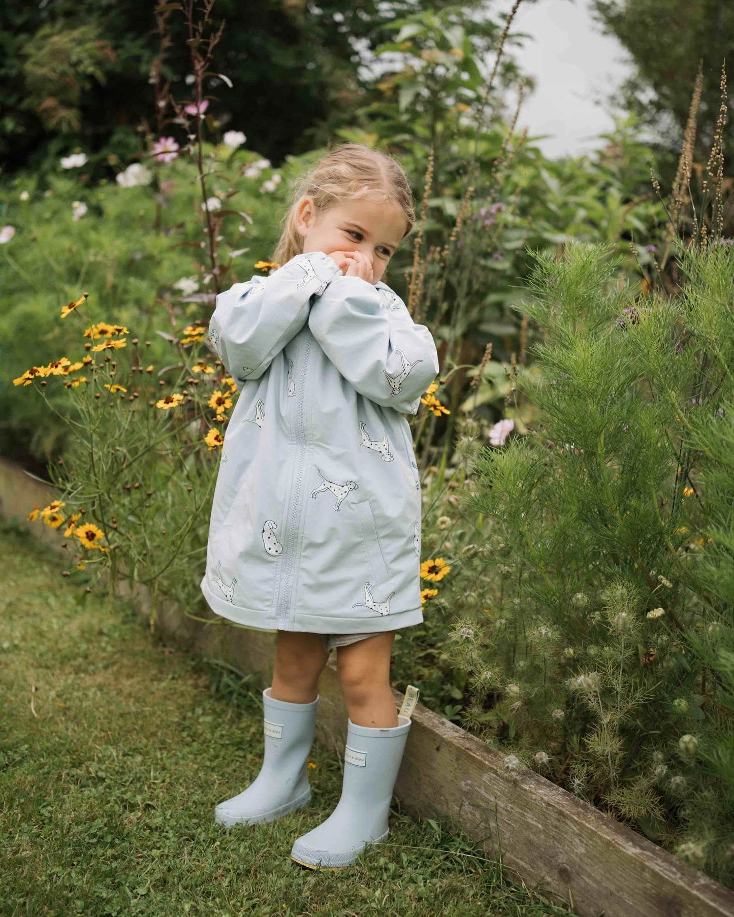 Holly and Beau Lifestyle of toddler girl in the garden wearing her dalmatian color changing raincoat