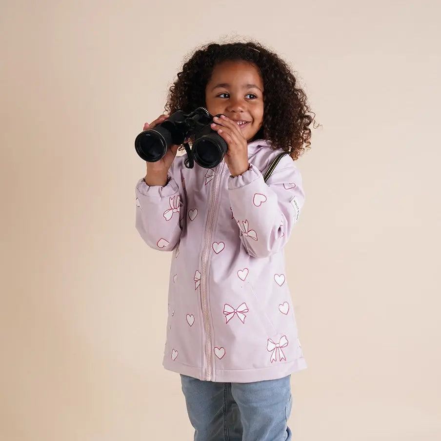 Girl smiling wearing the pink bows and hearts color changing raincoat by Holly and Beau