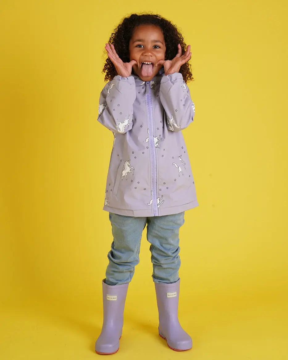 Holly and Beau Happy girl wearing the purple colour changing unicorn raincoat